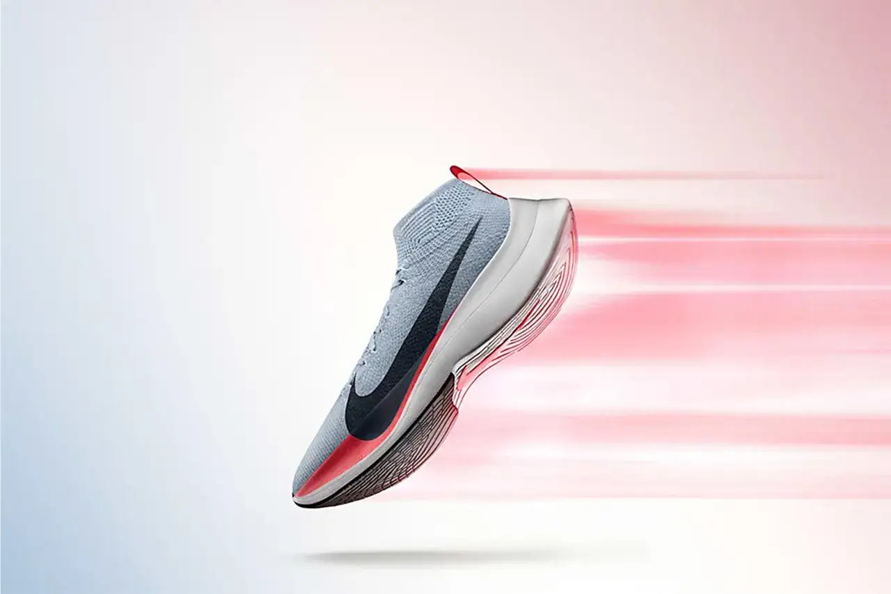 Szary but do szybkiego biegania Nike z czarnym logo, unoszący się na tle rozmytych, różowych pasów sugerujących prędkość.