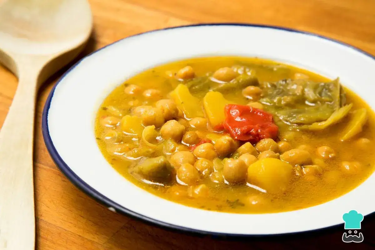Un plato humeante de garbanzos con patatas, pimientos y un trozo de pimiento rojo. Una deliciosa receta de garbanzos lista para disfrutar.