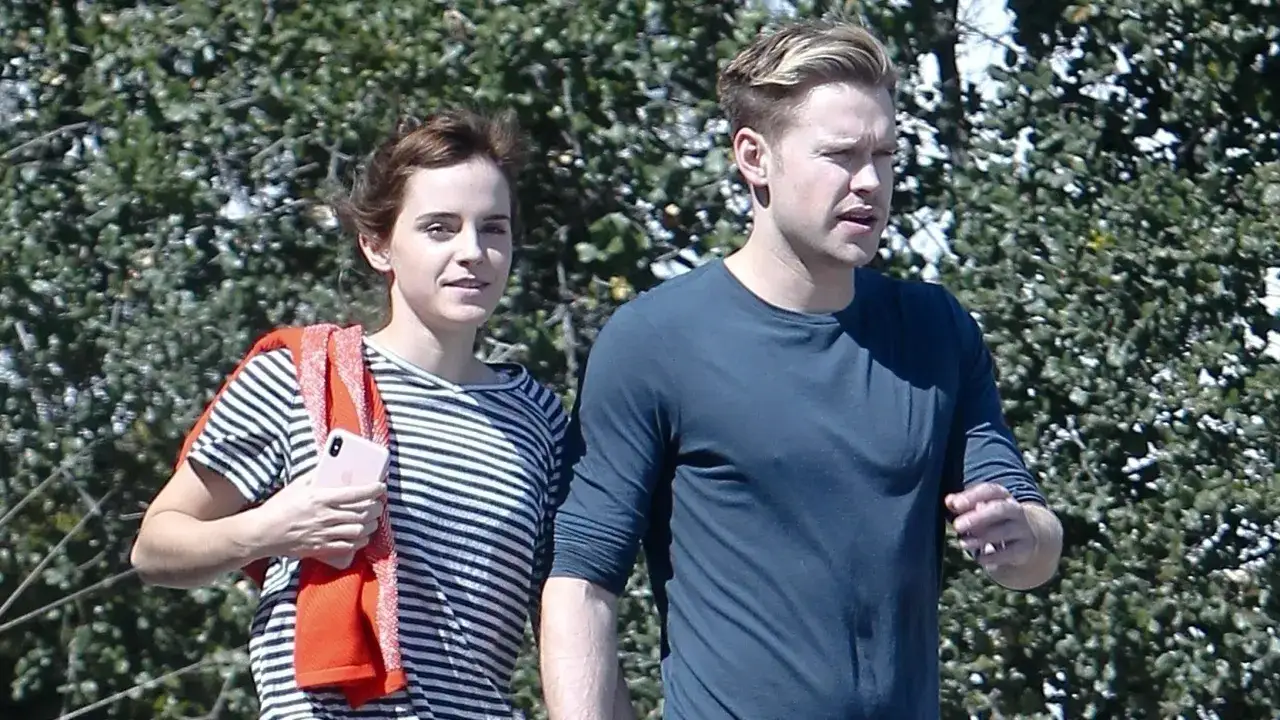 Emma Watson z mężem, w słoneczny dzień, spacerują wśród zieleni.