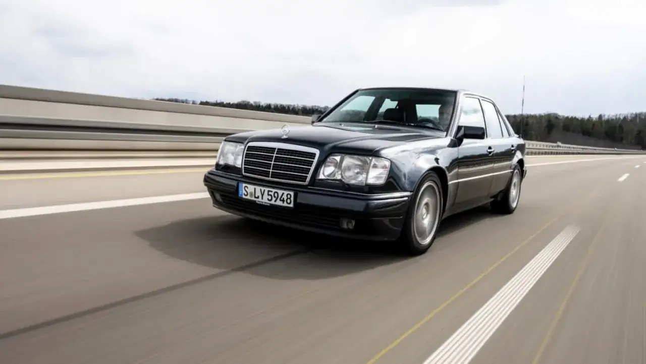 Czarny Mercedes 500E sunie po autostradzie, jego linia podkreśla moc i elegancję.