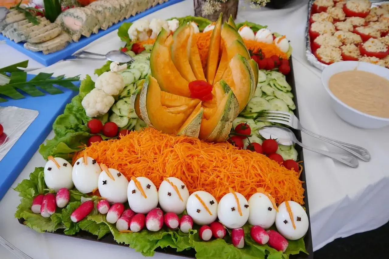 Un buffet froid de salades colorées : œufs décorés, carottes râpées, melon, concombres, tomates cerises et chou-fleur.