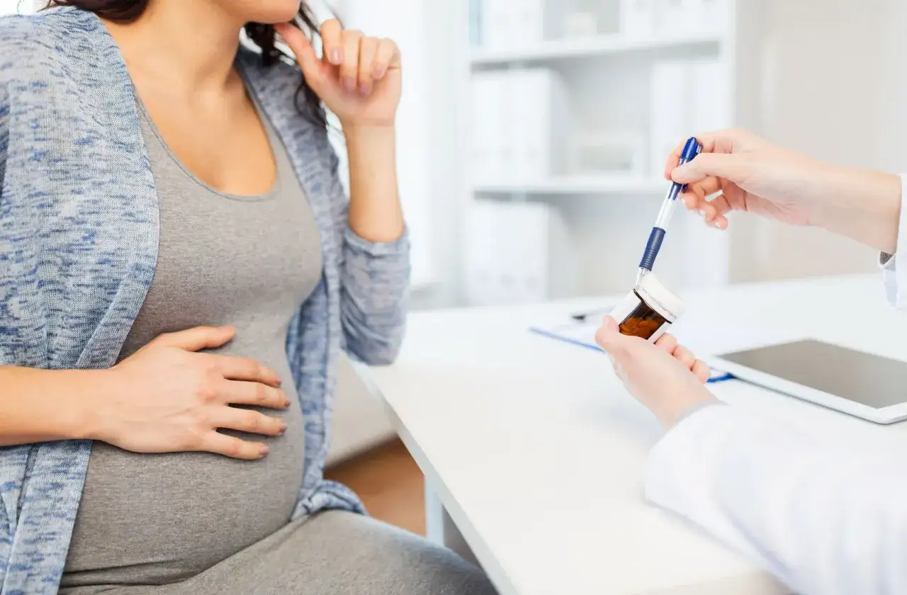 Lekarz pokazuje ciężarnej kobiecie buteleczkę z lekami, omawiając paracetamol w ciąży.