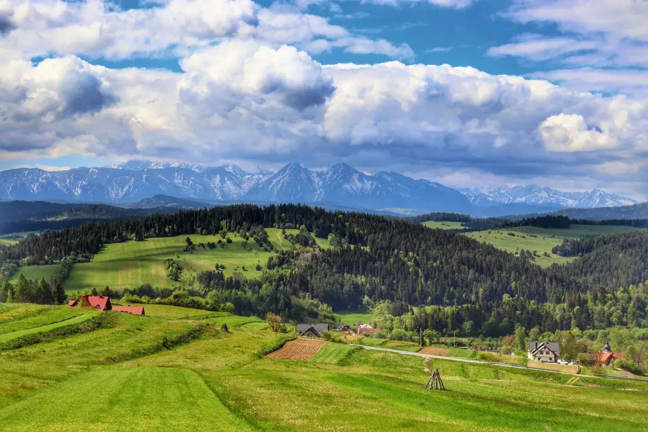 Malownicze **Sromowce Wyżne atrakcje** w Pieninach: zielone łąki, lasy i ośnieżone szczyty Tatr w tle.