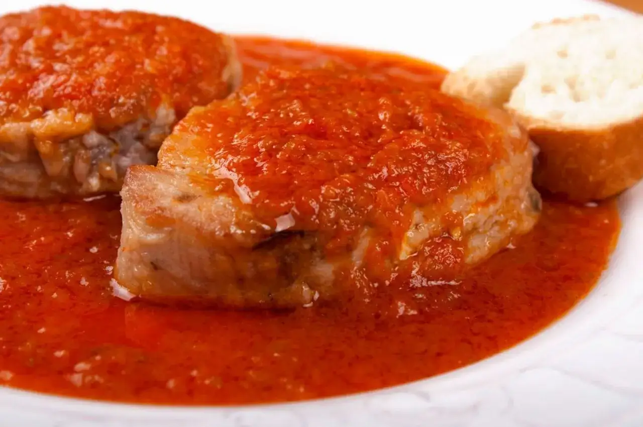 Bonito en salsa de tomate, un plato casero con un trozo de pan para mojar.