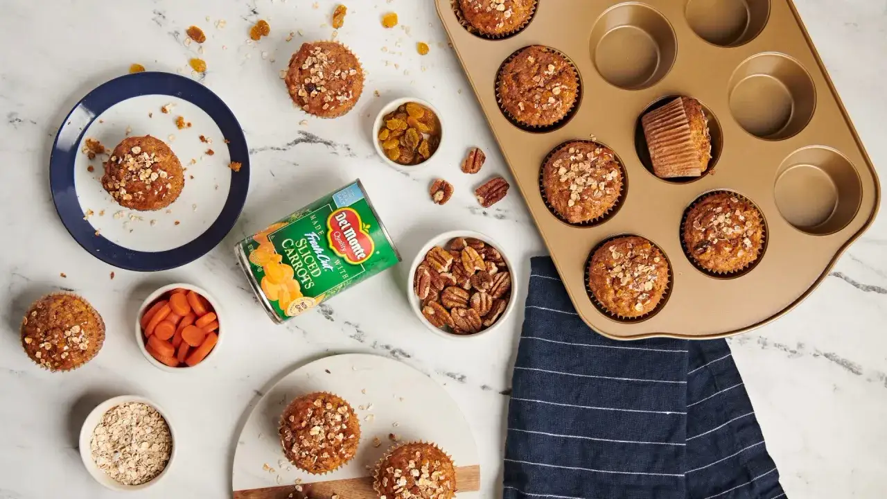Karottenmuffins rezept: Muffins mit Haferflocken, Rosinen und Nüssen, daneben Zutaten wie Karotten, Rosinen und Pekannüsse.