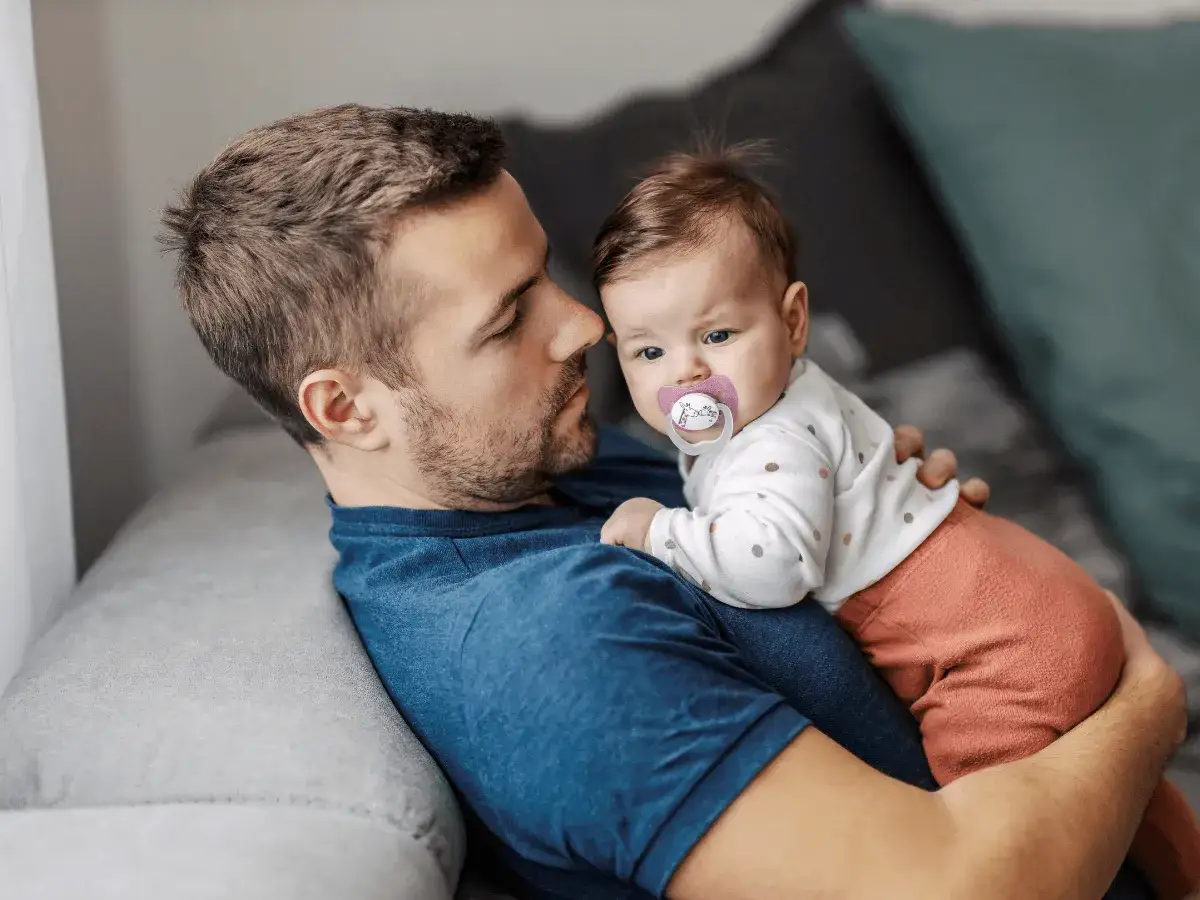 Tata na urlopie tacierzyńskim tuli swoje dziecko. Czas spędzony razem jest bezcenny.