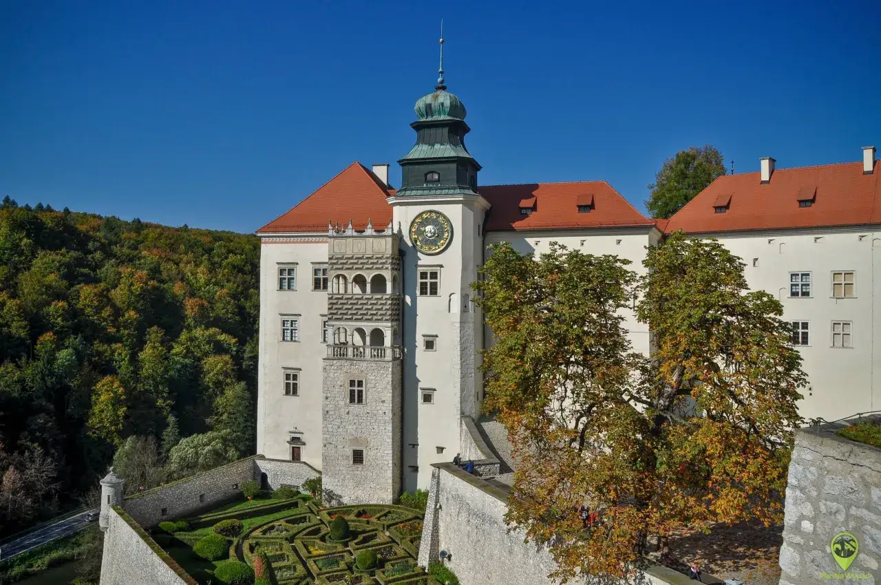 Ojcowski Park Narodowy: zamek z zegarem i ozdobnym ogrodem. Jesienne liście drzew dodają uroku.