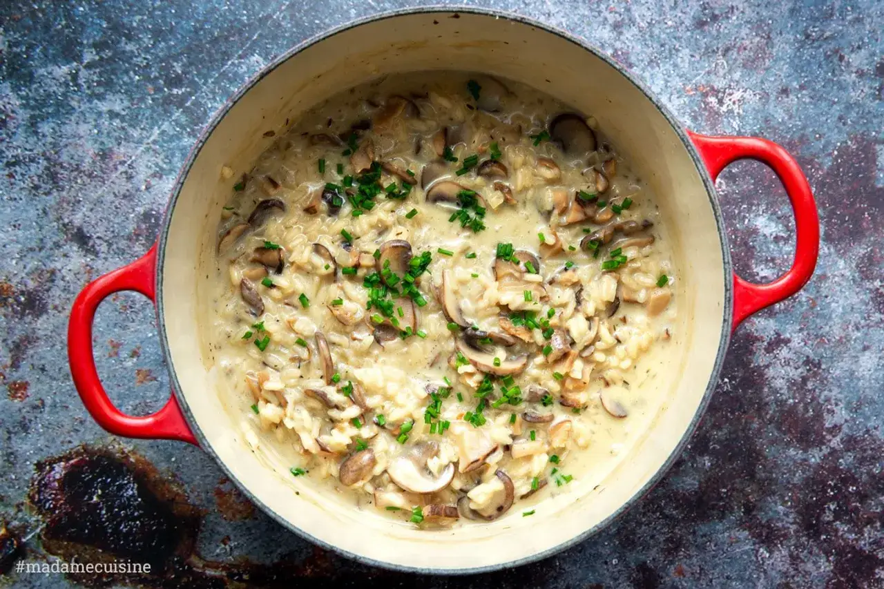 Cremiges Pilzrisotto, ein klassisches Risotto Rezept, in einem roten Gusseisentopf, garniert mit frischem Schnittlauch.