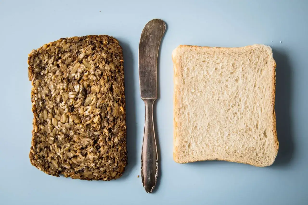 Zwei Brotscheiben, eine Vollkorn und eine Weißbrot, liegen neben einem Messer. Wie viel Kalorien hat eine Scheibe Toast?