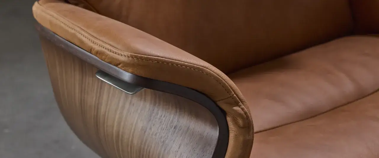 Detalj av en stol med armst&ouml;d i mjukt anilin skinn och en b&ouml;jd tr&auml;struktur.