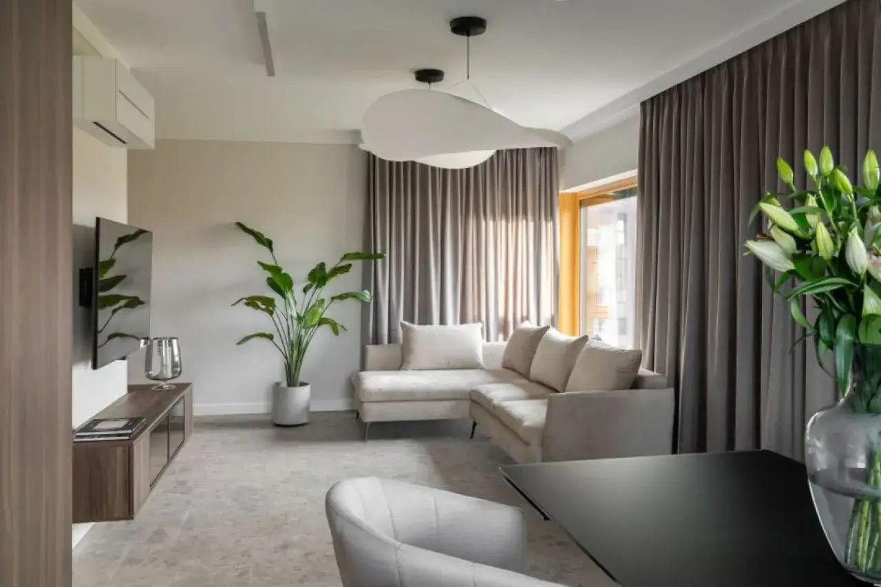 Nowoczesny salon z narożną sofą, telewizorem i dyskretnym rozmieszczeniem halogenów na suficie, tworzącym przyjemną atmosferę.