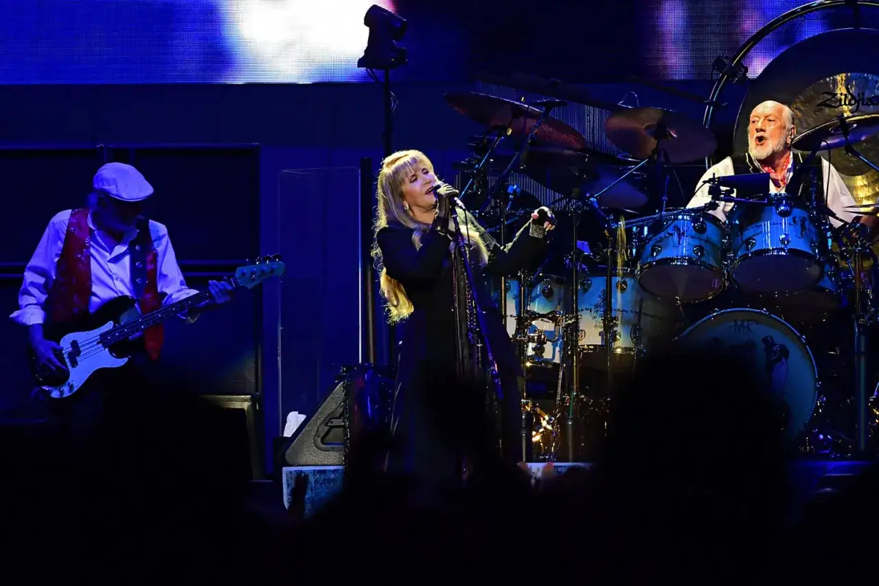 Stevie Nicks śpiewa, a Mick Fleetwood gra na perkusji. W tle basista, tworząc niezapomniane **fleetwood mac utwory**.