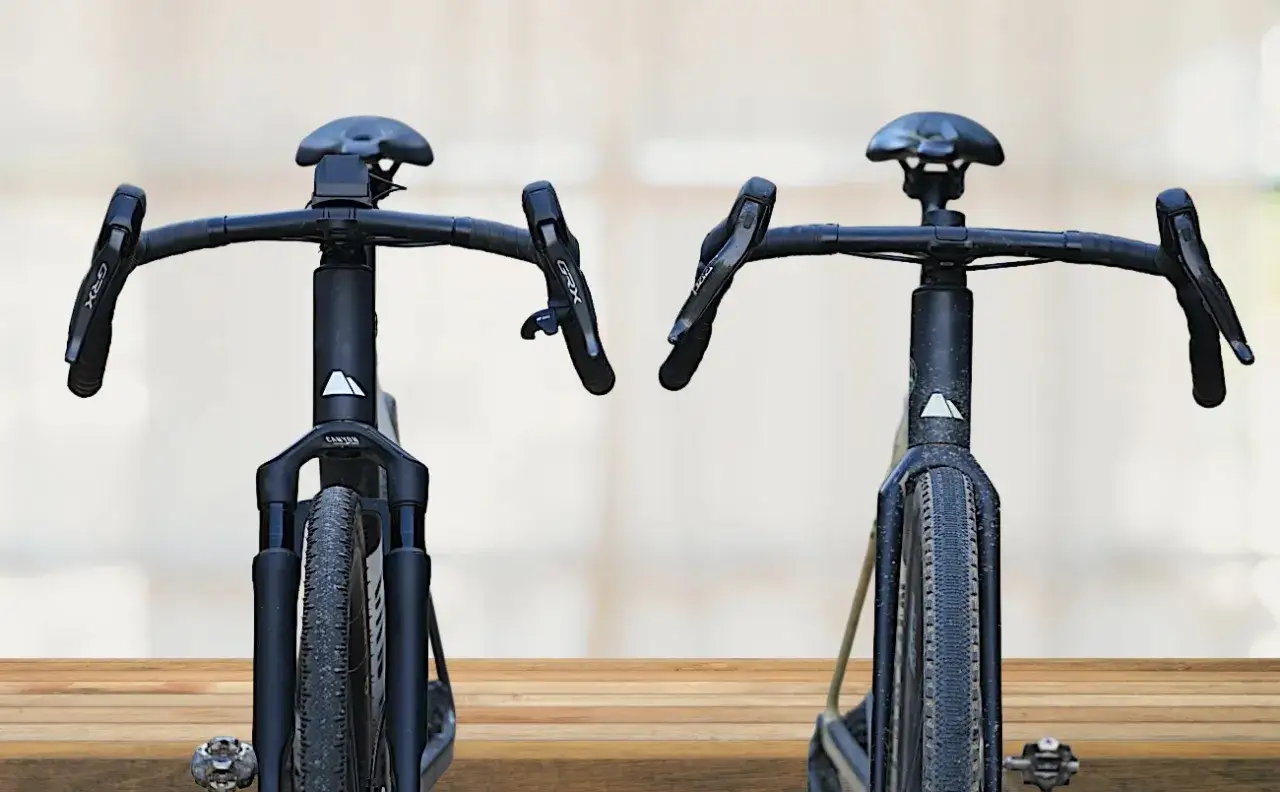 Two black gravel bikes, front view. The bike on the left has a suspension fork, answering the question: do gravel bikes have suspension?