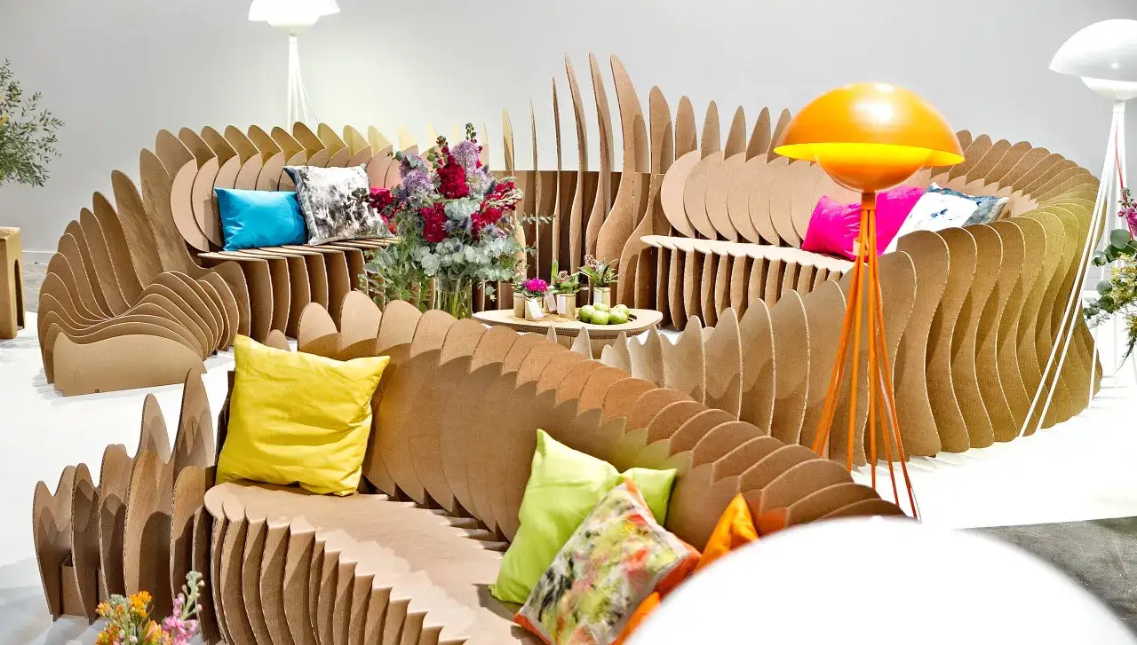 Salon moderne en carton ondulé, avec coussins colorés et lampe orange. Une déco originale et écologique.