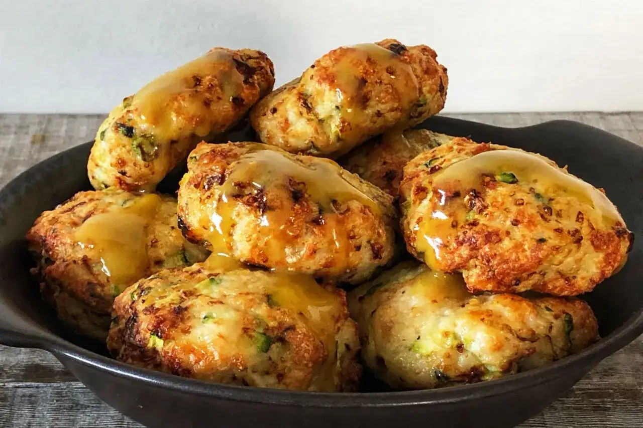 Złociste kotleciki z cukinii, polane sosem, wyglądają apetycznie. Takie cuda można wyczarować w **air fryer co to** za urządzenie, które je przygotowało?