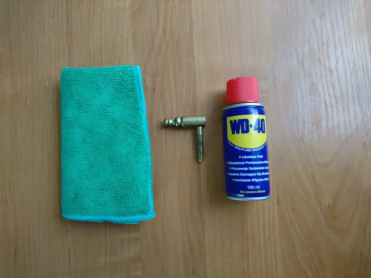 Ściereczka, mosiężny element i puszka WD-40 – wszystko gotowe do czyszczenia mosiądzu.