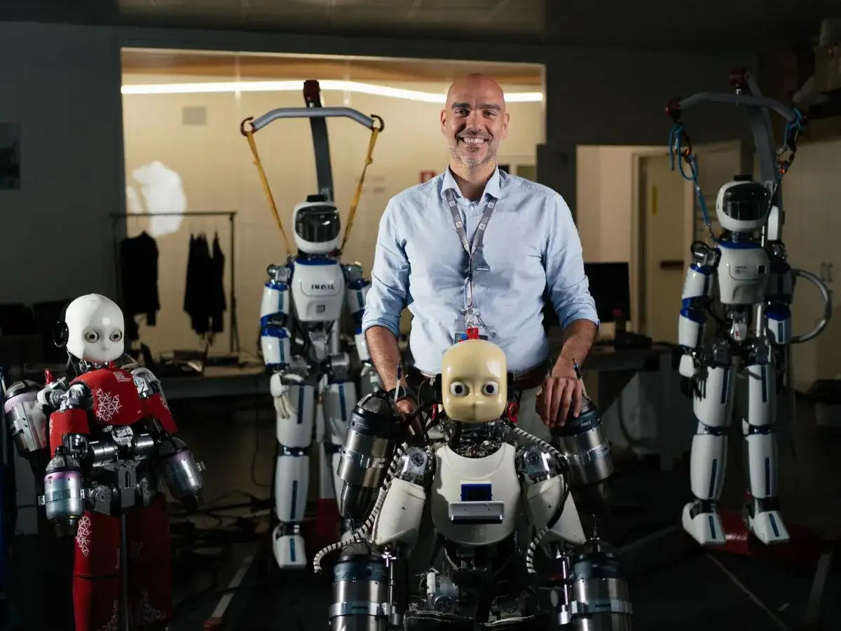 Uomo sorridente con robot umanoidi. Forse un futuro per i laureati in fisica disoccupati?