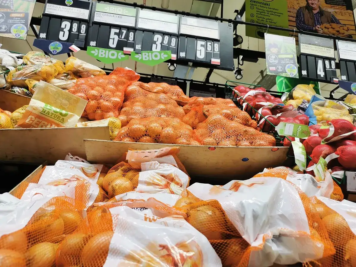 Aktualne ceny warzyw i owoców: cebula od 3,99 zł, ziemniaki od 4,99 zł. Widać też jabłka i inne produkty.