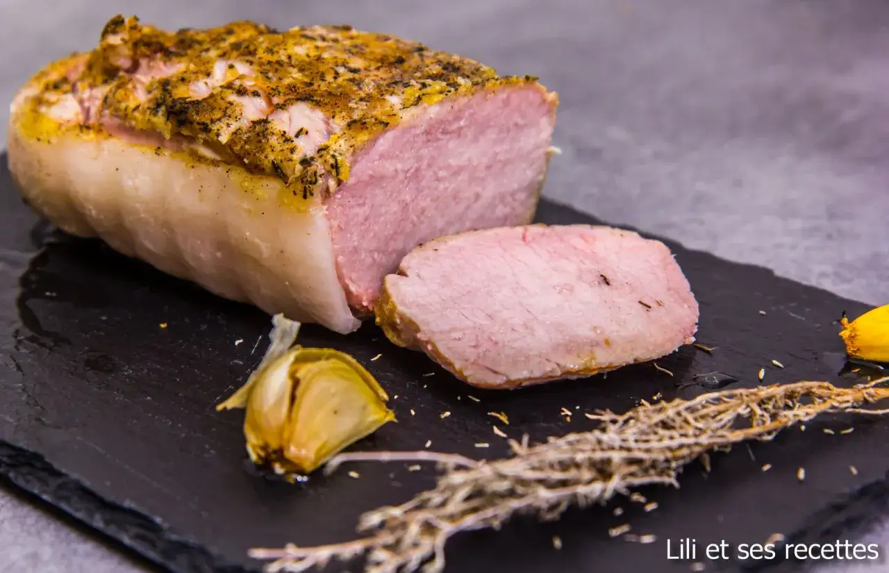 Un délicieux roti de porc rosé, tendre et juteux, assaisonné d'herbes et servi avec de l'ail rôti.