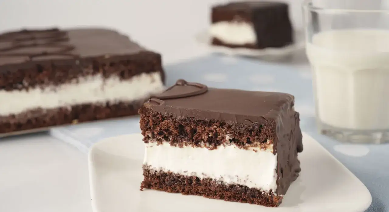 Délicieux gâteau au chocolat et à la crème, parfait pour une recette kinder délice. Un verre de lait complète ce tableau gourmand.