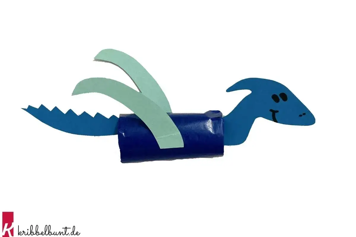 Blauer Papier-Dinosaurier mit Zacken und Fl&uuml;geln, bastelndes Kind f&uuml;r ein Kita-Projekt.