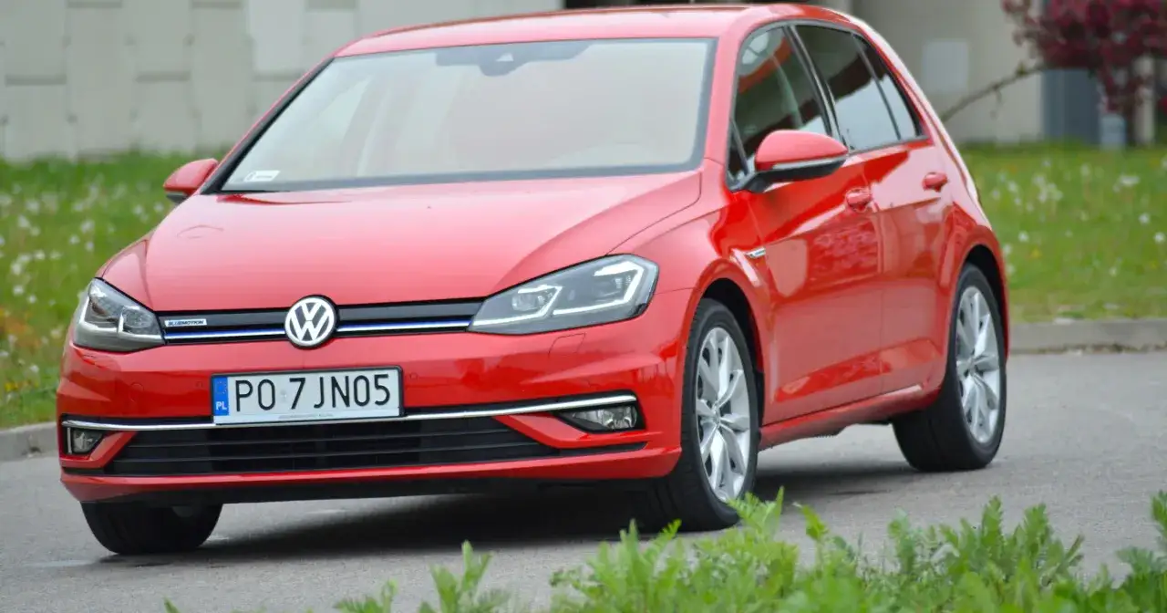 Czerwony Volkswagen Golf z napisem BLUEMOTION, co oznacza, że jest to wersja oszczędna i ekologiczna.