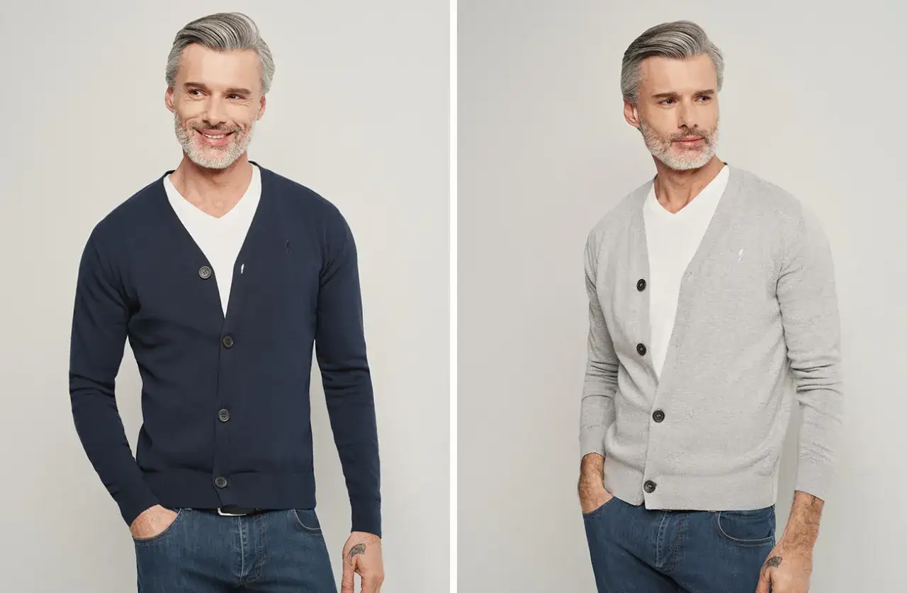 Elegancki mężczyzna pokazuje, jak nosić kardigan: granatowy i szary model z białym t-shirtem i jeansami.