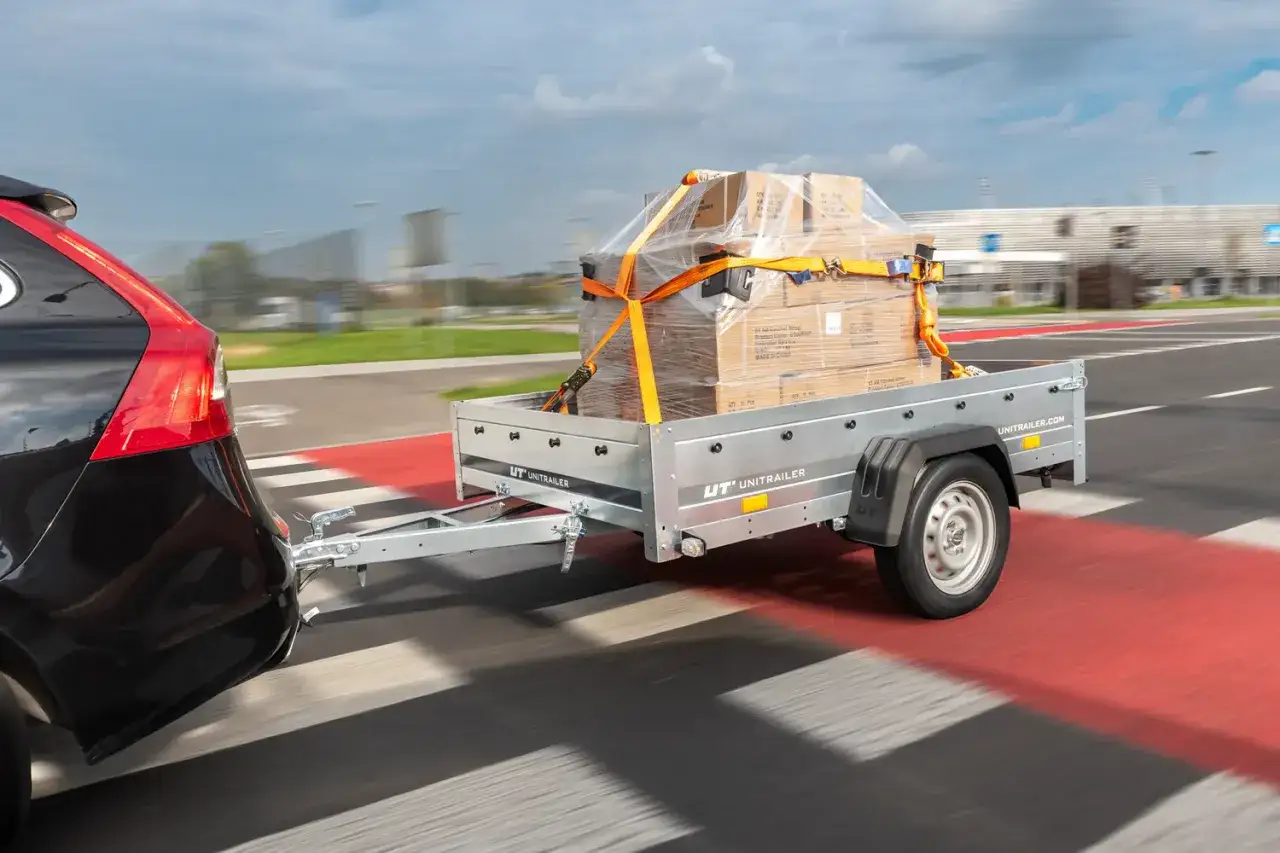Bezpieczna jazda z przyczepą pełną paczek. Towar zabezpieczony pasami, gotowy do transportu.