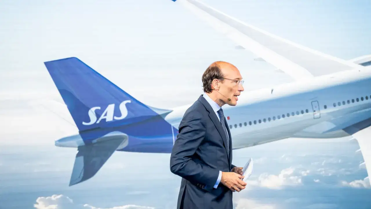SAS chef i kostym talar framf&ouml;r en storbildssk&auml;rm med ett flygplan och SAS-logotypen.