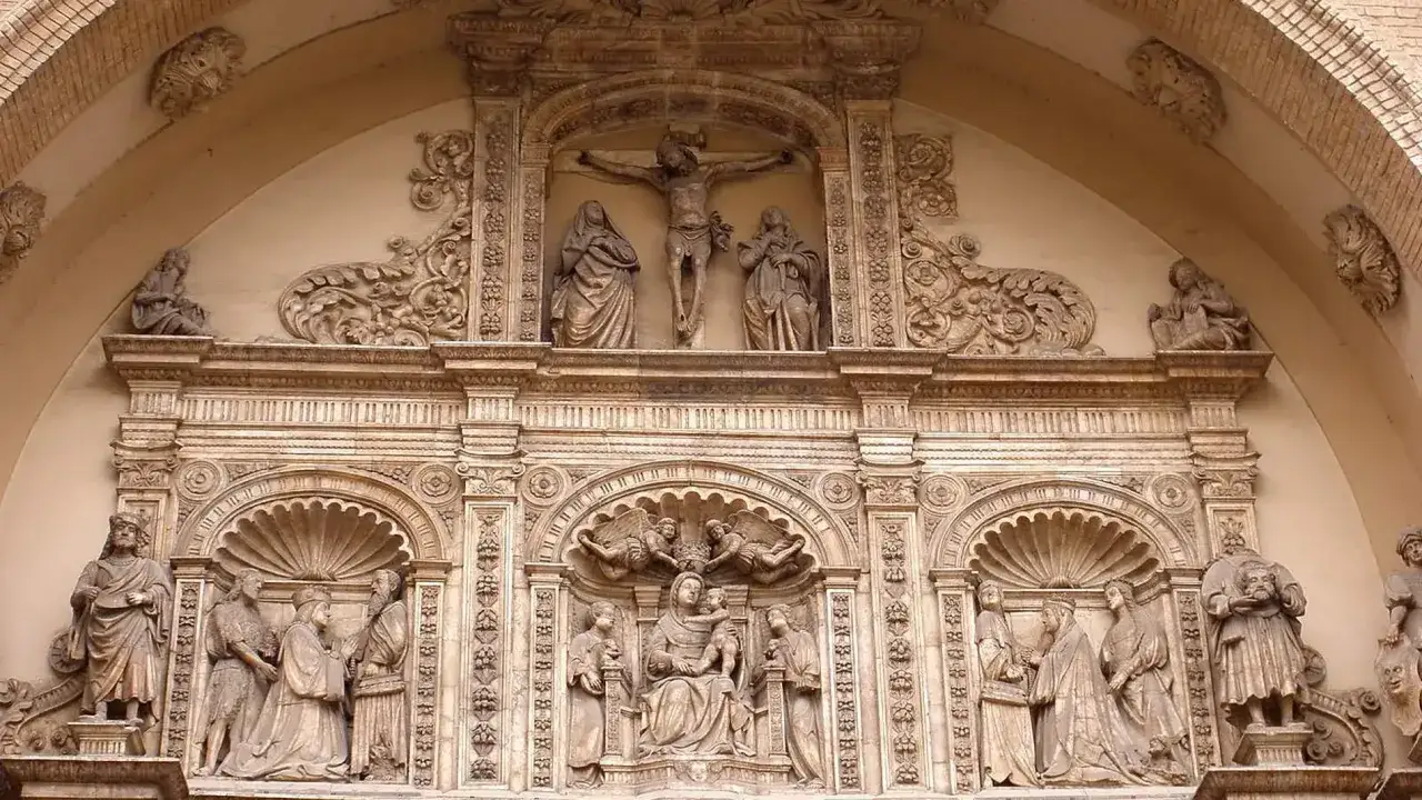 Detalle de la fachada de una iglesia en Zaragoza. Esculturas de la crucifixión, la Virgen con el Niño y otras figuras religiosas.