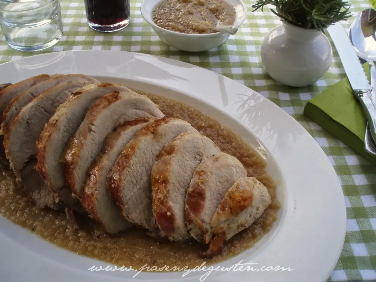 Lomo de cerdo asado en rodajas, servido sobre una sabrosa salsa de manzana. Un plato perfecto para cualquier ocasión.