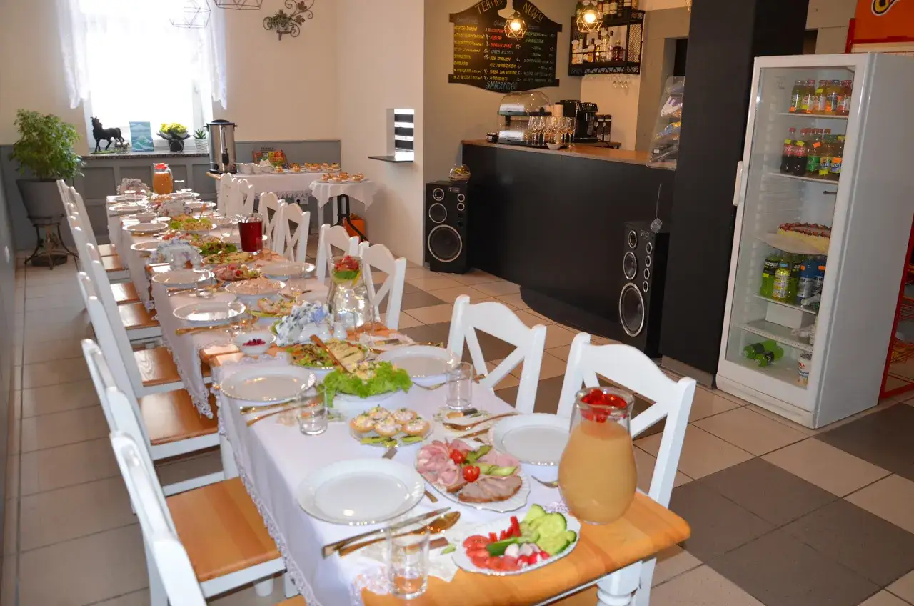 Ustawiony stół z jedzeniem i napojami, idealne miejsce, gdzie na obiad w Łodzi. Białe krzesła i obrusy tworzą elegancką atmosferę.