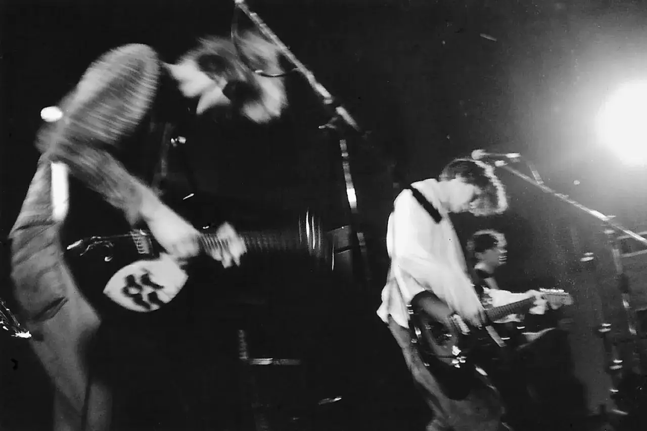 Muzycy grający na gitarach na scenie, w tle jasne światło. To właśnie shoegaze co to za gatunek muzyczny?