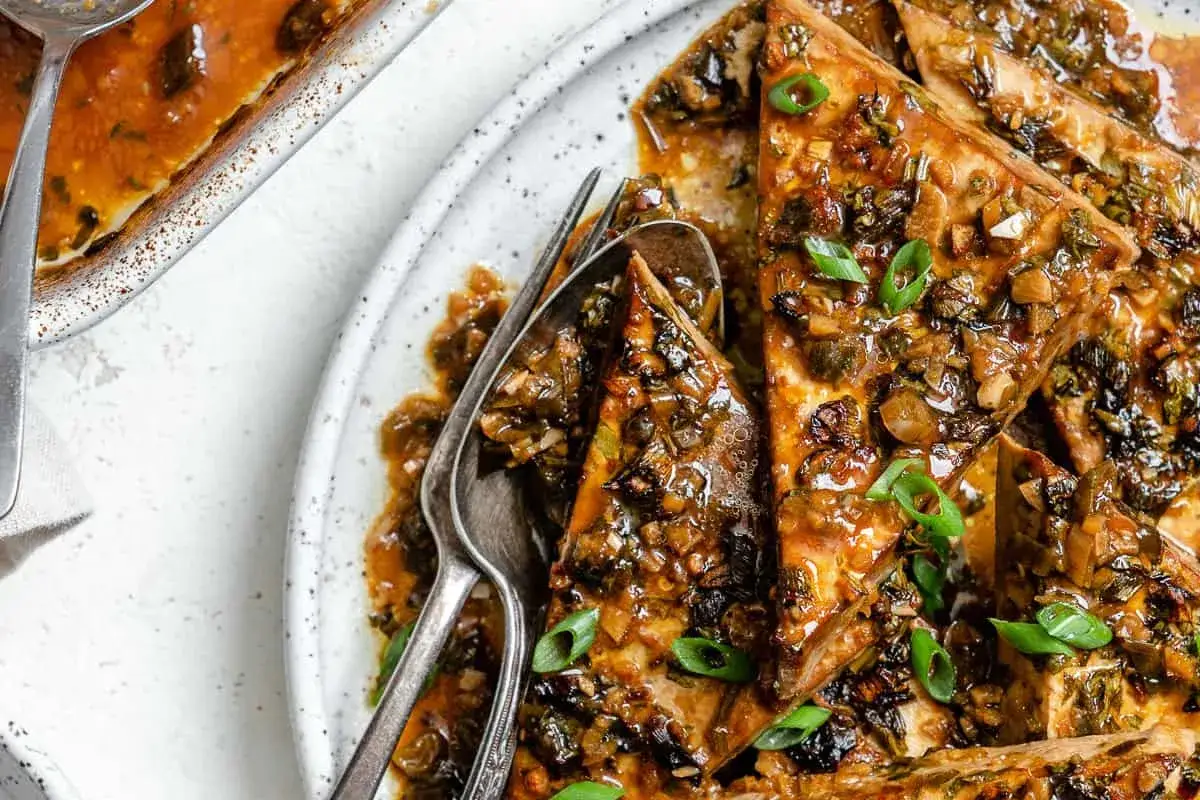 Triángulos de tofu marinado cubiertos con una salsa sabrosa y cebolleta picada.