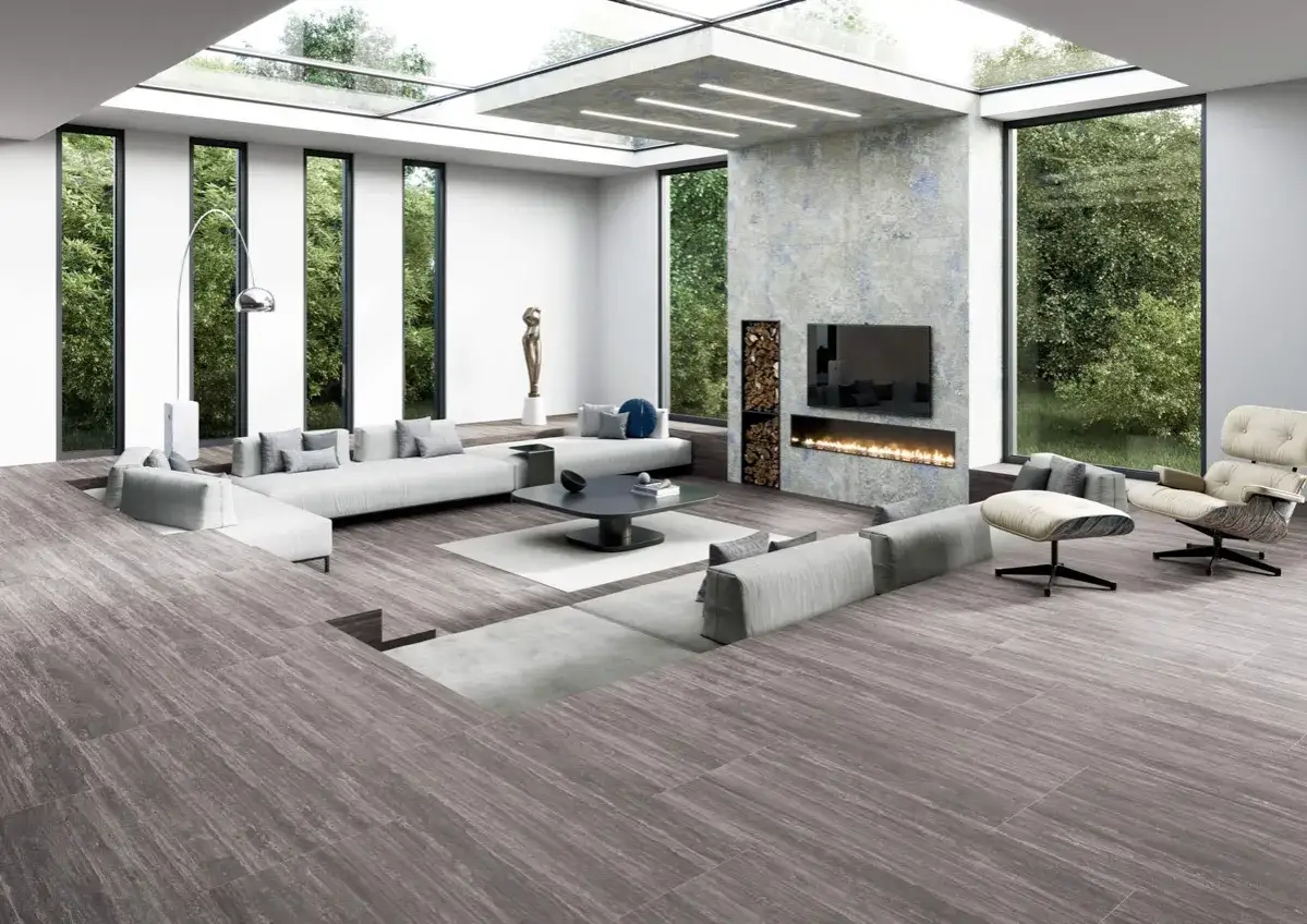Elegante salón con chimenea, sofás modulares y grandes ventanales. El suelo de madera, con distintos tipos de parquet, aporta calidez.