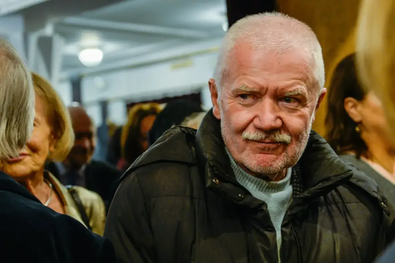 Tadeusz Borowski aktor, w życiu prywatnym, w otoczeniu ludzi, z siwą brodą i wąsami, w czarnej kurtce.