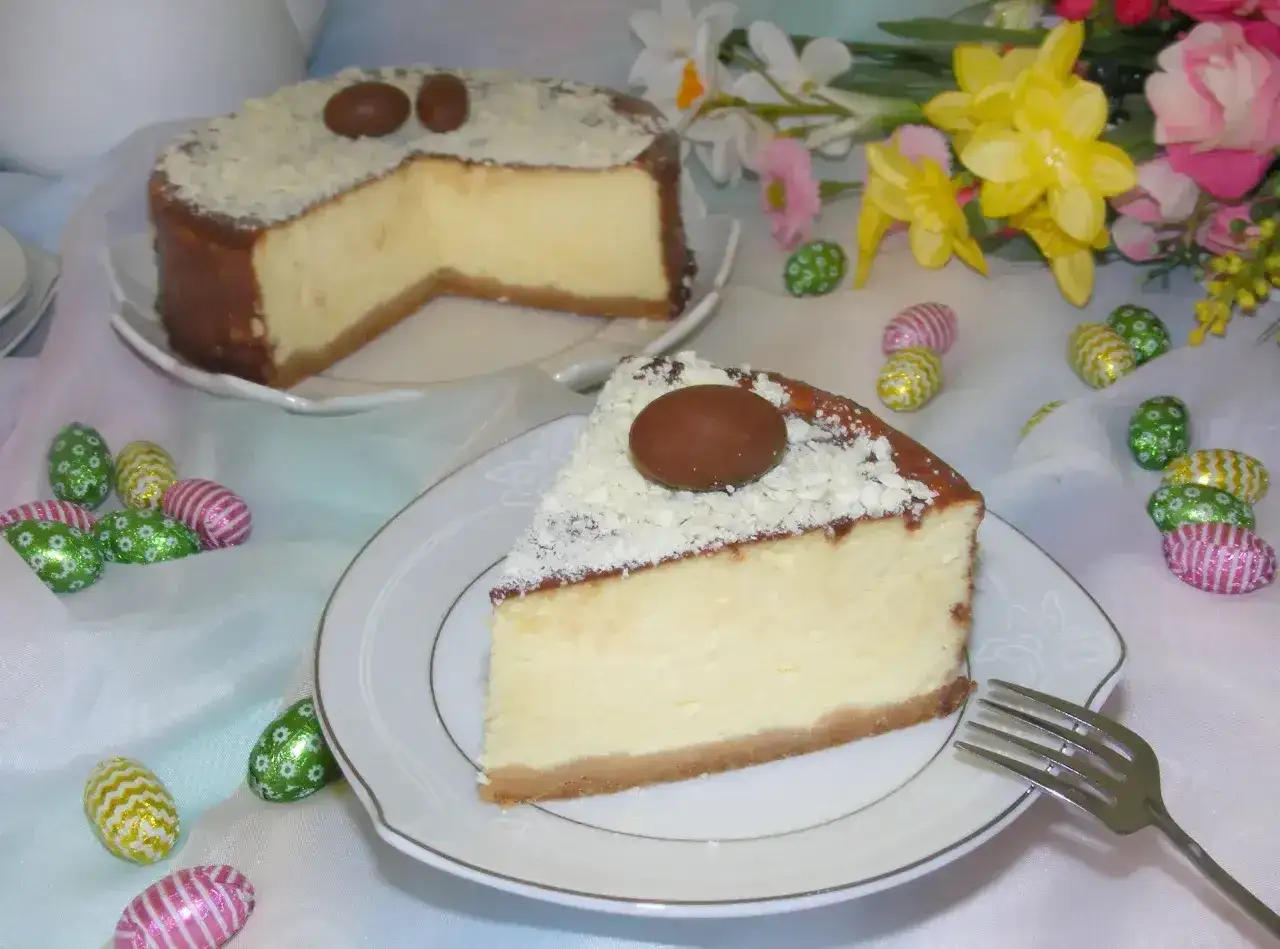 Pyszny sernik z mascarpone, udekorowany czekoladowymi jajeczkami i wiórkami białej czekolady, na wielkanocnym stole.