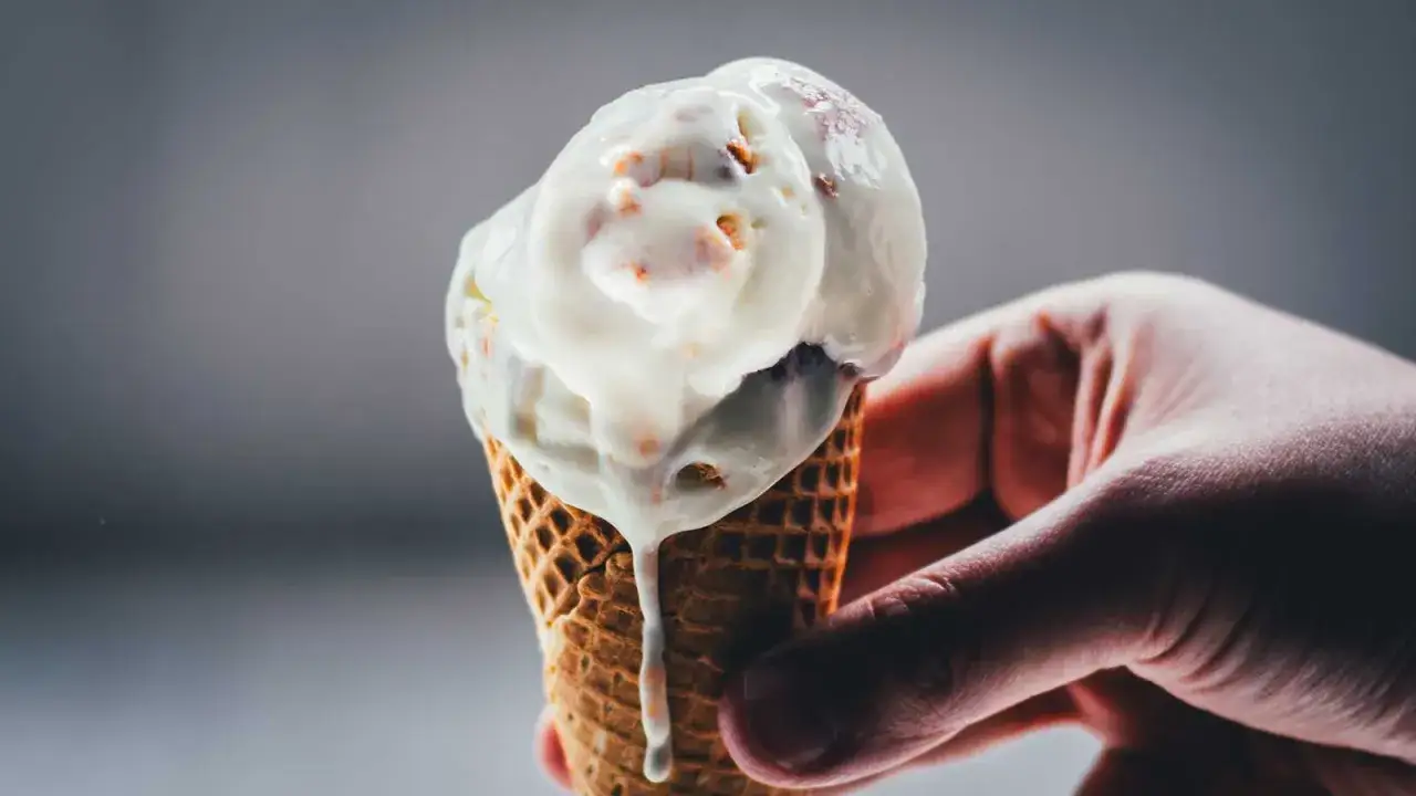 Eine Hand hält ein schmelzendes Rhabarber-Eis in einer Waffel.