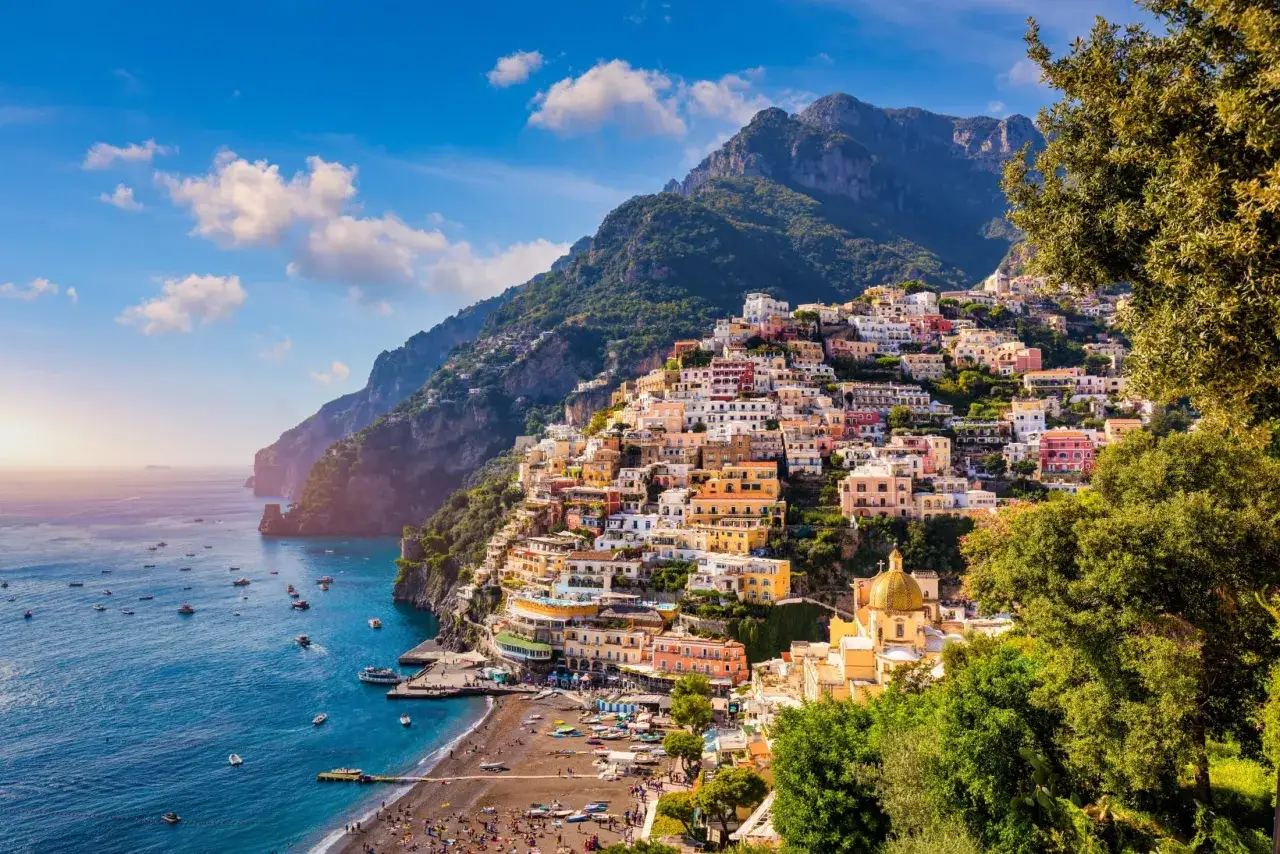 Kolorowe domy wspinają się po zboczu góry nad błękitnym morzem. Widok na słynne miasteczko na **Amalfi Coast**.