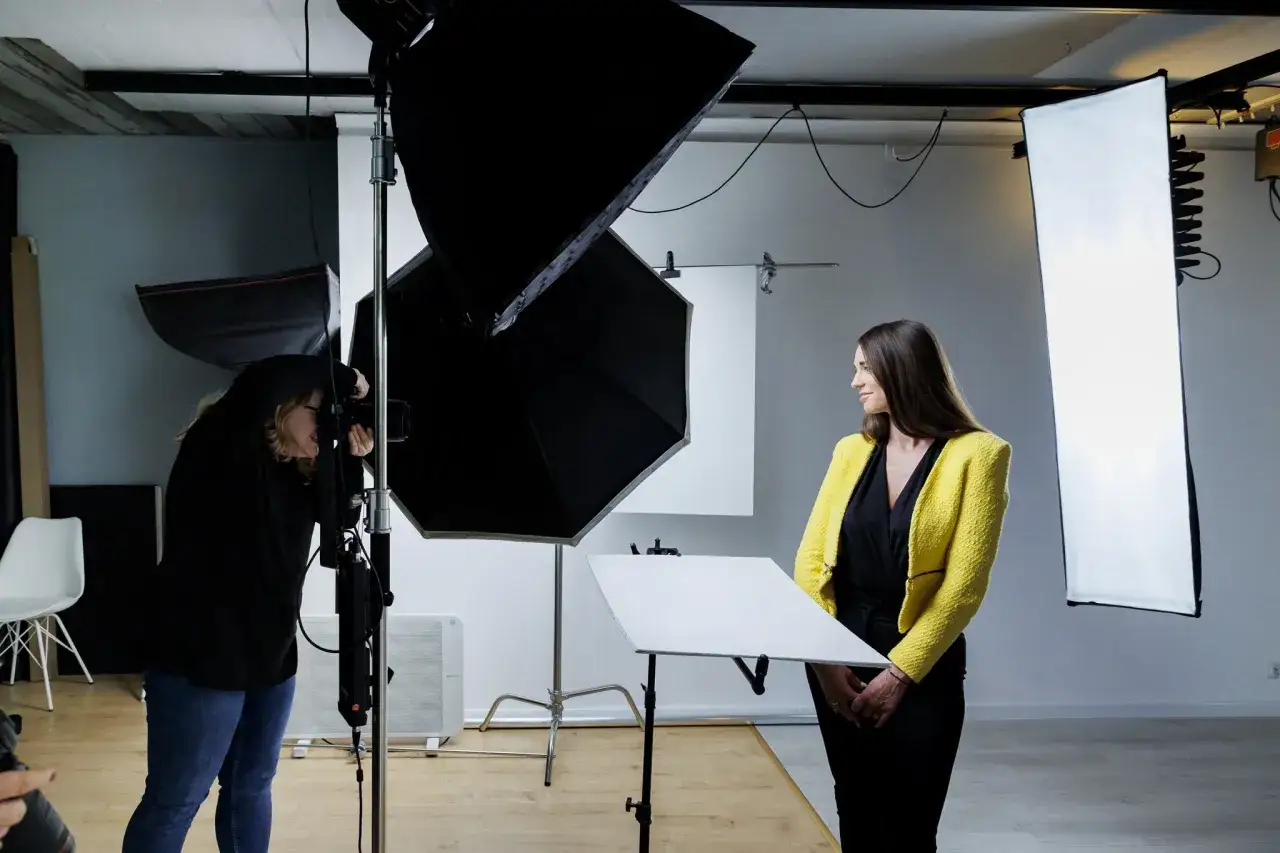 Kobieta na kursie fotografa ćwiczy portretowanie modelki w studio.