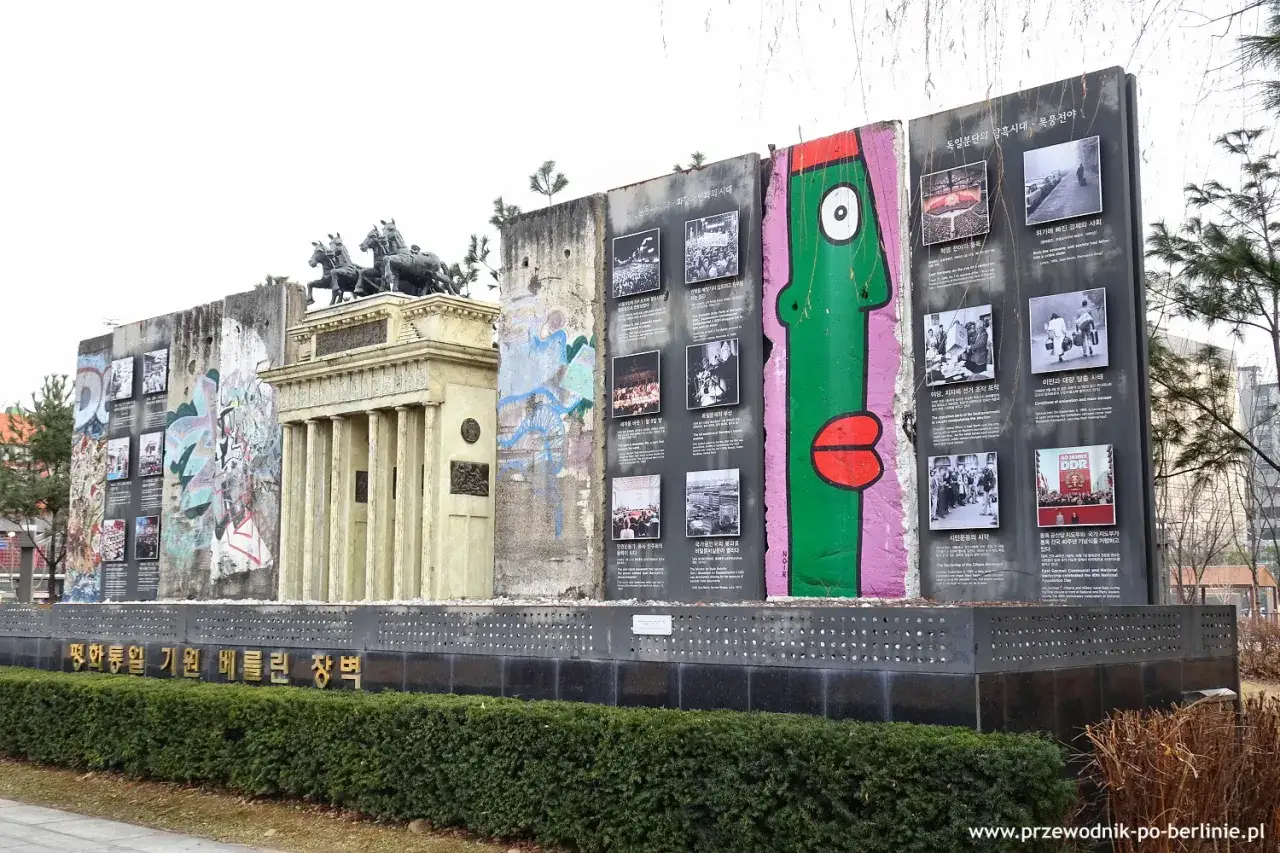 Fragment muru berlińskiego z graffiti i zdjęciami upamiętniający zjednoczenie Niemiec.