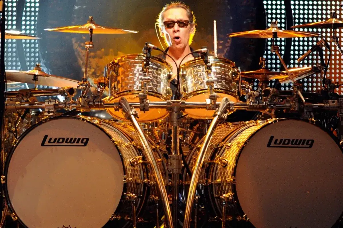Alex Van Halen w okularach przeciwsłonecznych gra na błyszczącym, złotym zestawie perkusyjnym Ludwig.