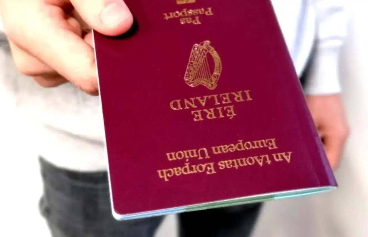 Dłoń trzyma paszport Irlandii. Czy do Irlandii potrzebny jest paszport? Tak, ten dokument potwierdza tożsamość.