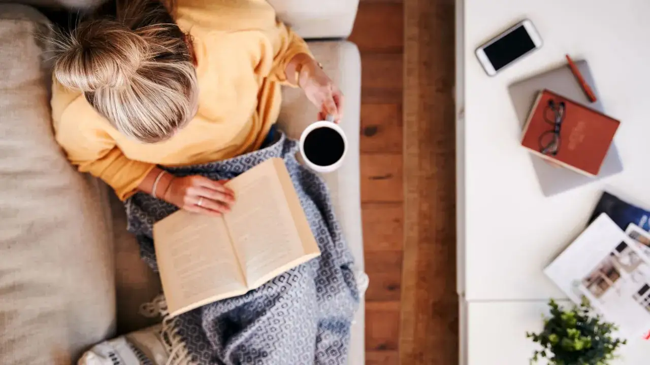 Gemütliche Lesestunde auf dem Sofa mit einer Tasse Kaffee. Ob der Kaffee die Blase reizt, ist bei so entspannter Lektüre nebensächlich.
