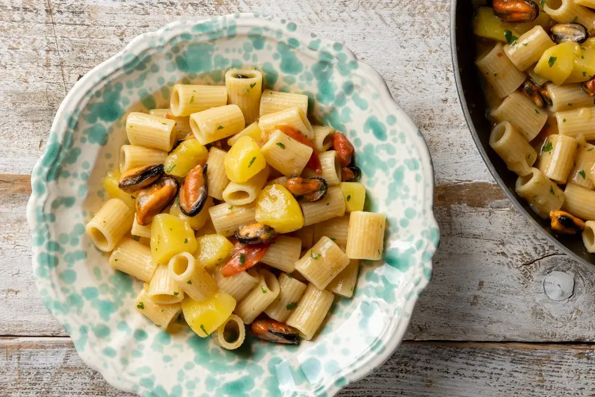 Un piatto invitante di pasta patate e cozze, con pezzi di patate dorate e cozze succulente, condito con erbe aromatiche.