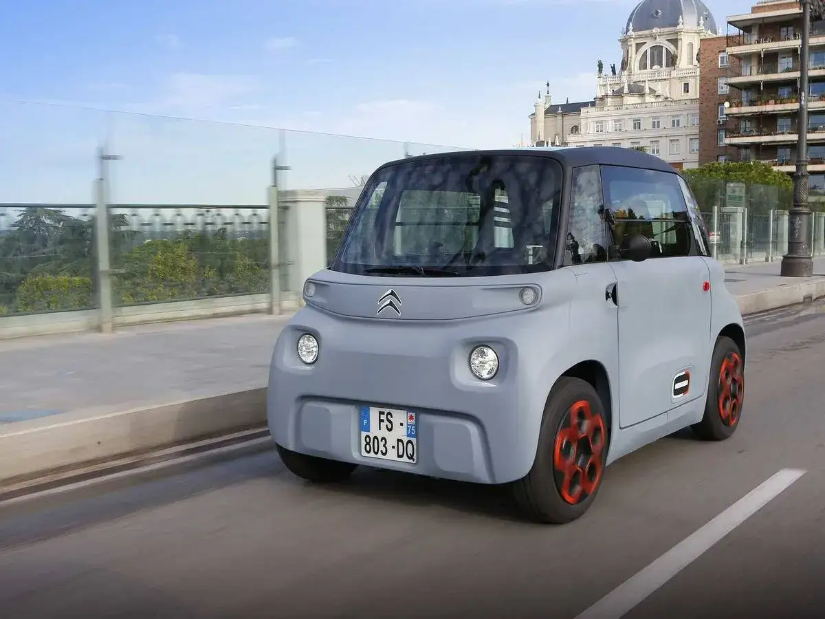 Coche eléctrico gris con detalles naranjas circulando por Madrid. Descubre las ventajas coche eléctrico Madrid y disfruta de la ciudad.