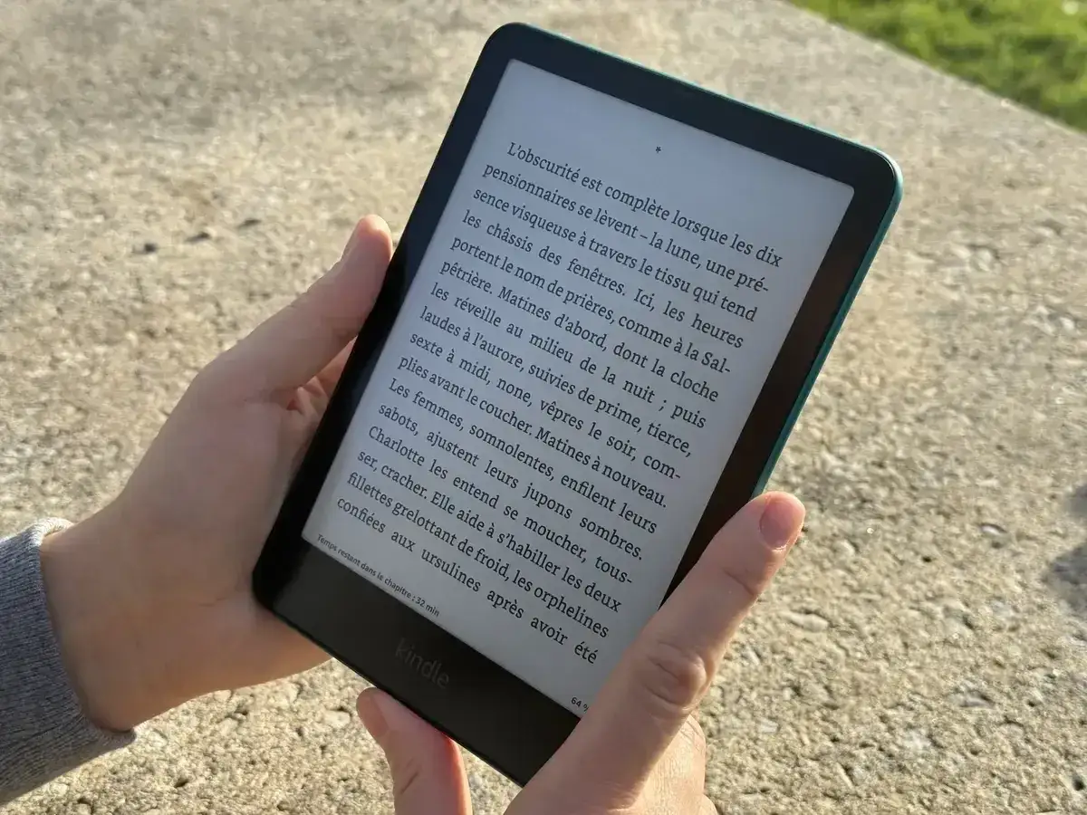 Main tenant une liseuse Kindle, lisant un livre prot&eacute;g&eacute; par adobe drm.