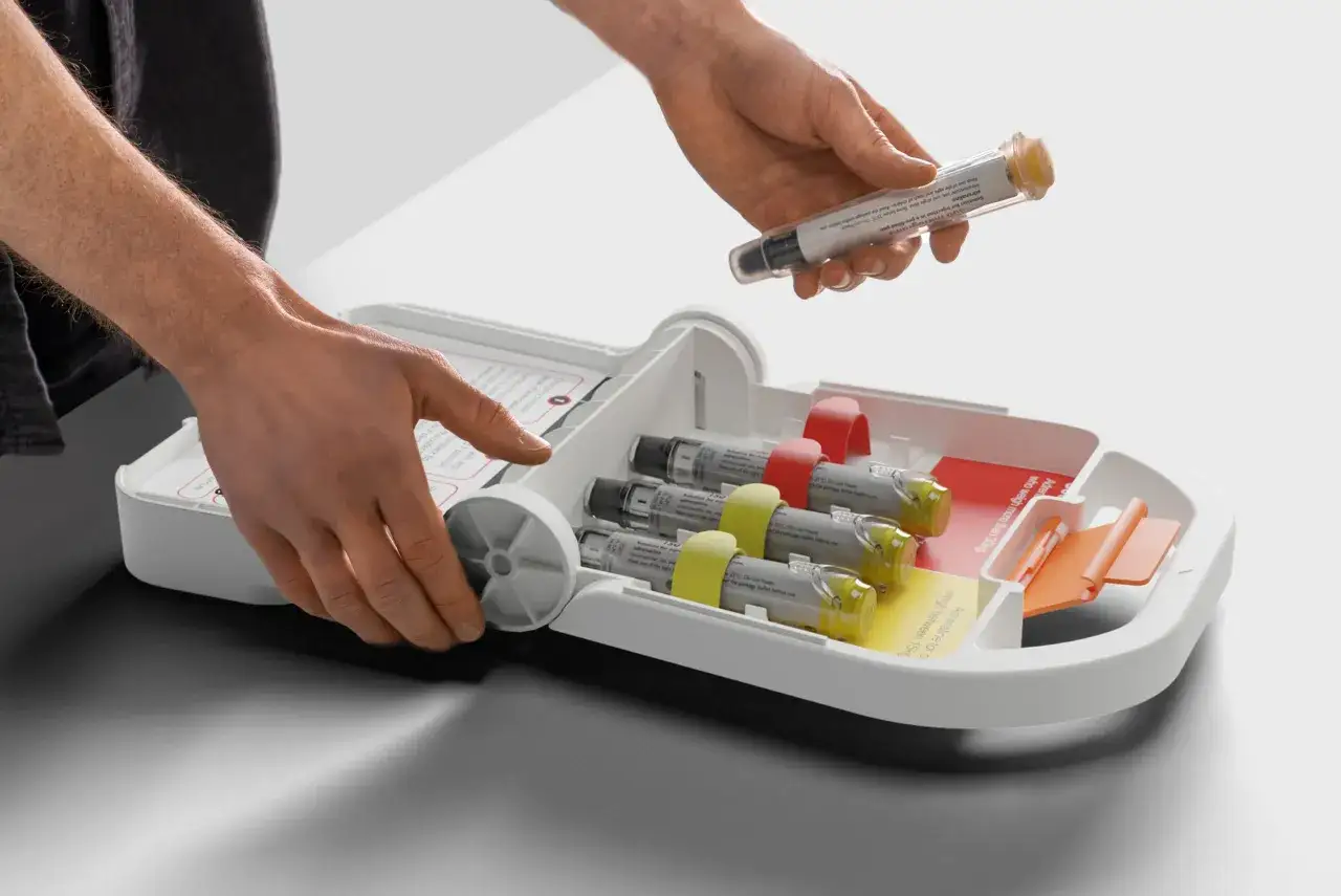 H&auml;nde nehmen Adrenalin-Autoinjektor aus einer Box, bereit f&uuml;r eine anaphylaktische Reaktion.