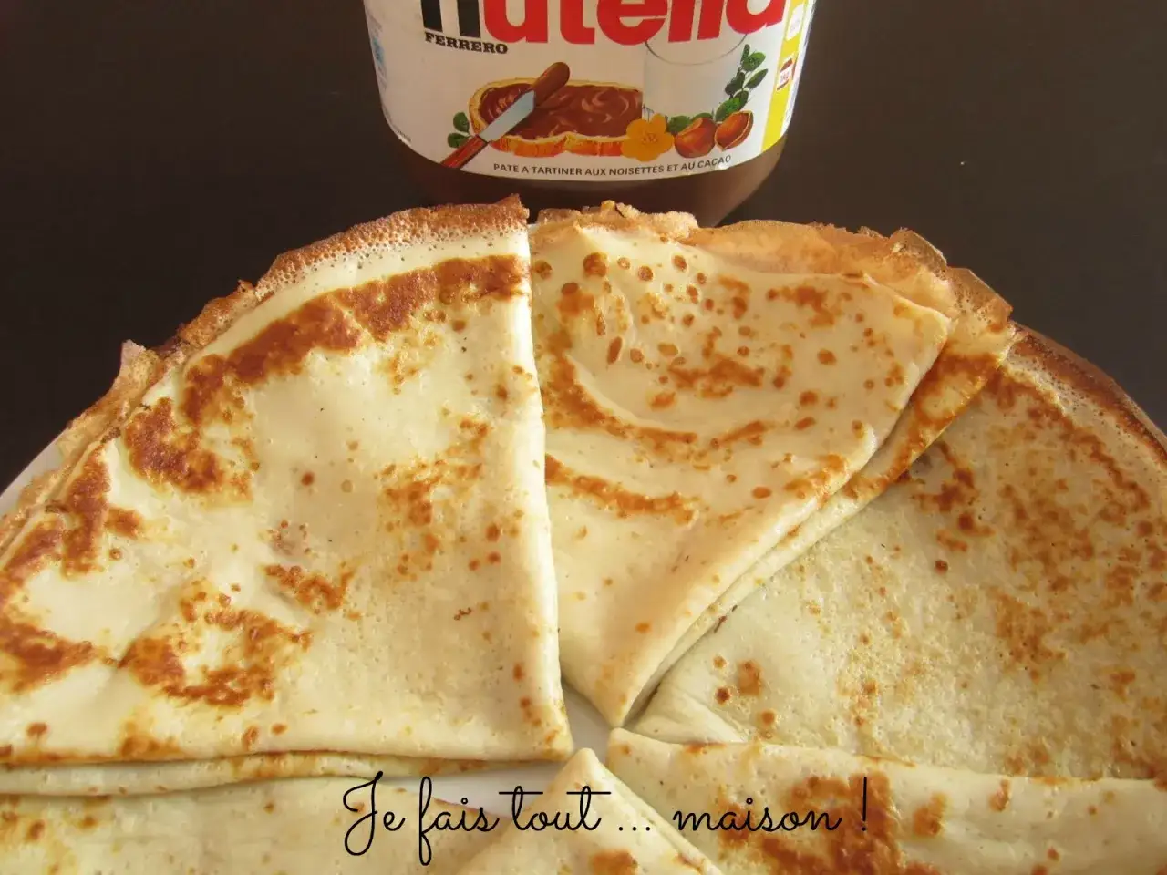 Cr&ecirc;pes dor&eacute;es, pr&ecirc;tes &agrave; &ecirc;tre garnies. Une recette maison pour le plaisir, avec un pot de Nutella en arri&egrave;re-plan.