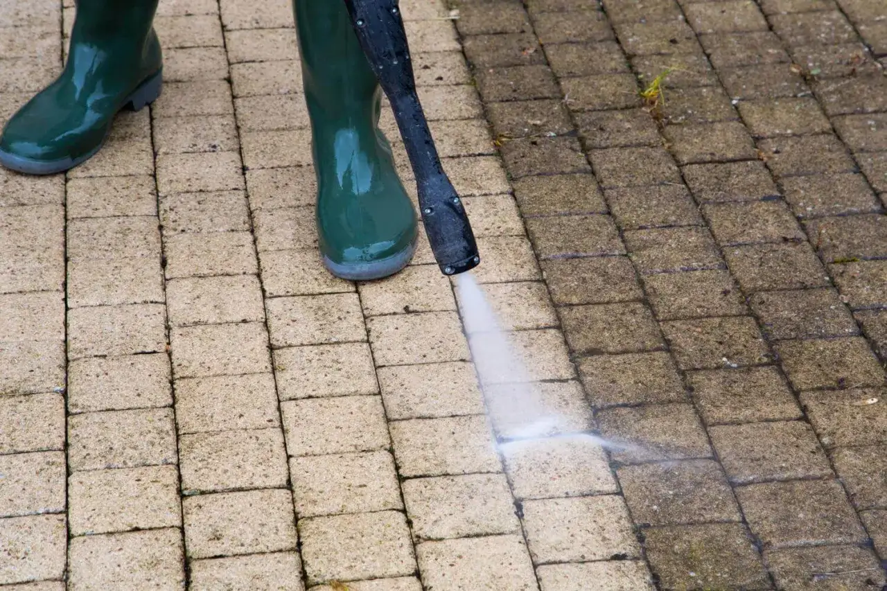 Utilisation d'un nettoyeur haute pression pour comment détruire la mousse dans une cour. Les bottes vertes protègent des éclaboussures.